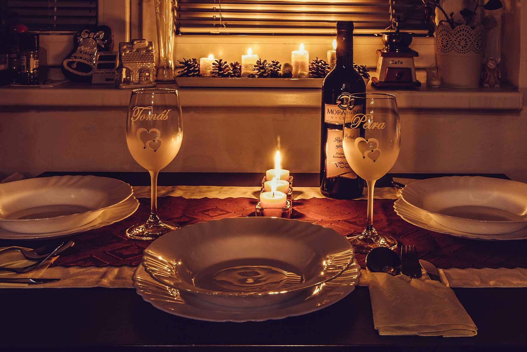 Cena romántica con copas grabadas y botella de vino.