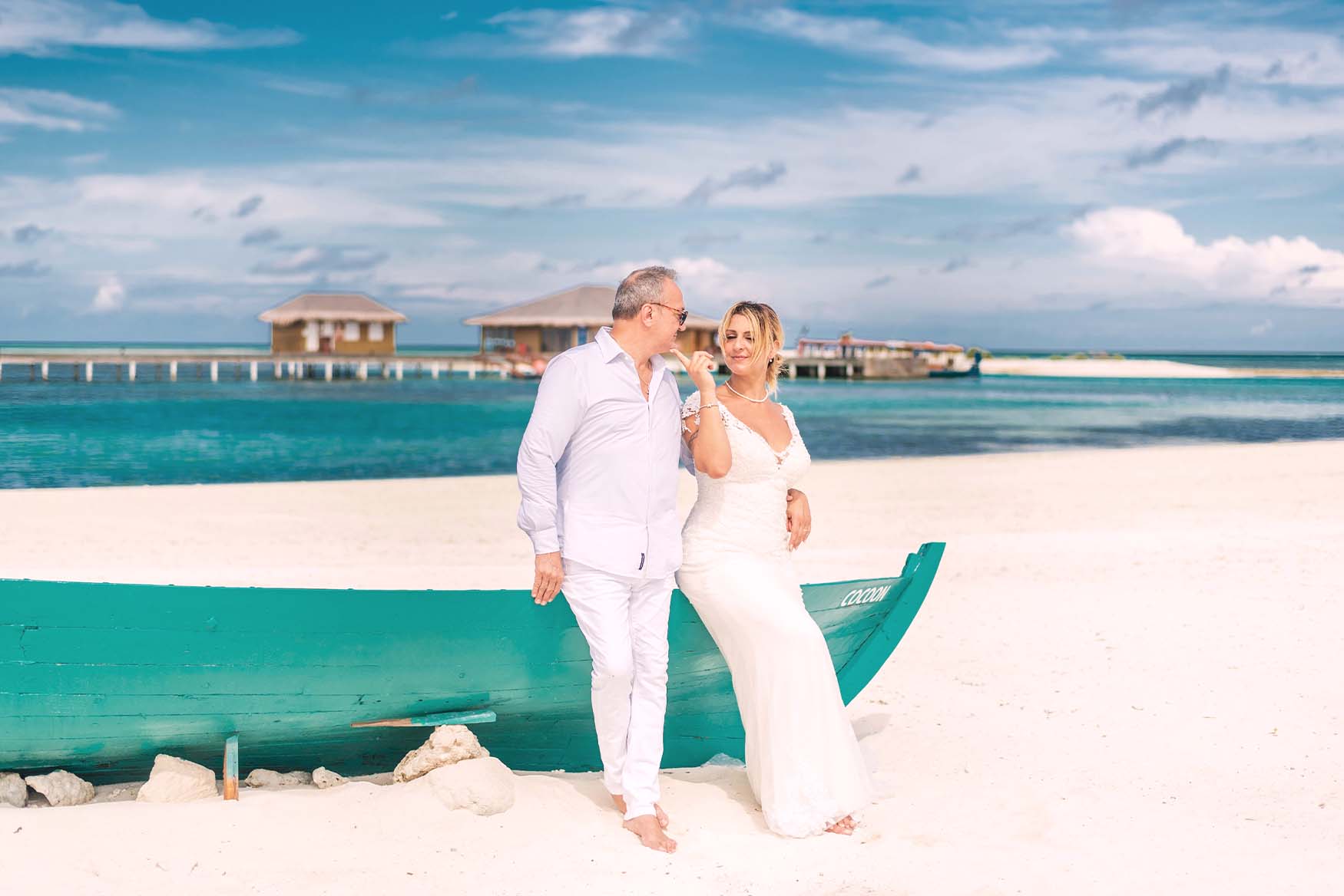 Pareja de pie en la playa con el mar de fondo.
