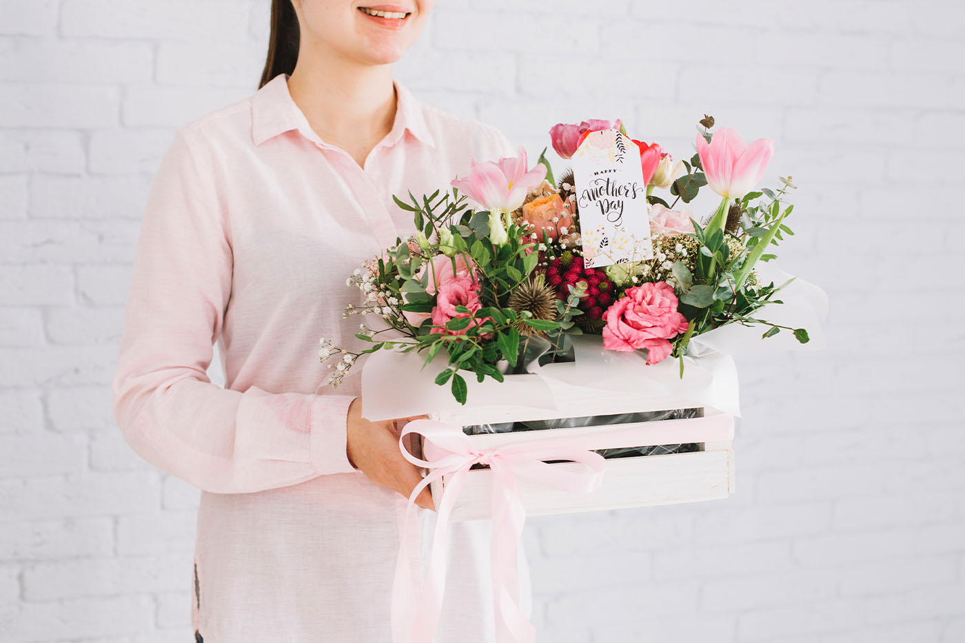 Mujer sostiene un arreglo floral en una caja de madera.