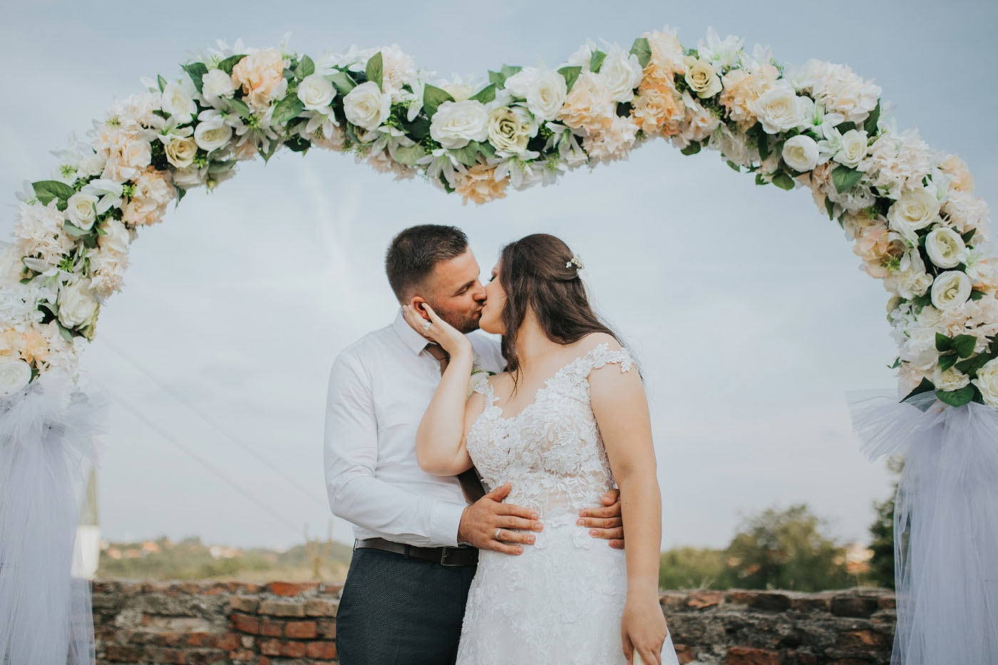 Pareja de recién casados bajo un arco de flores.
