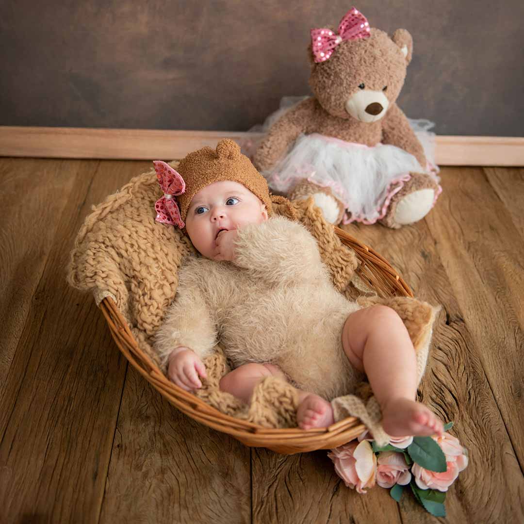Bebé en una canasta y un oso de peluche.