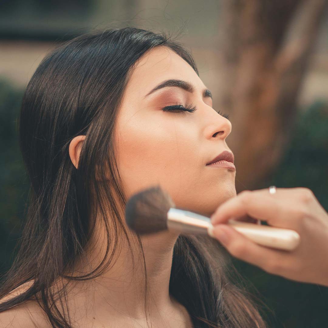 Mujer cierra los ojos mientras es maquillada.