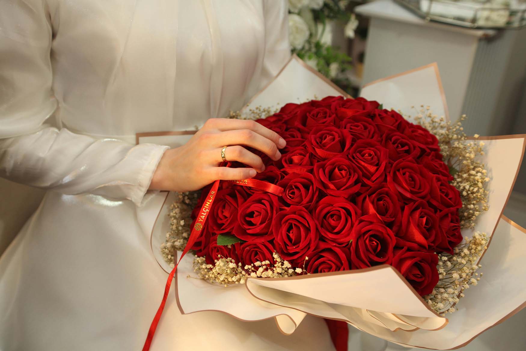 Manos sostienen un ramo de rosas rojas.
